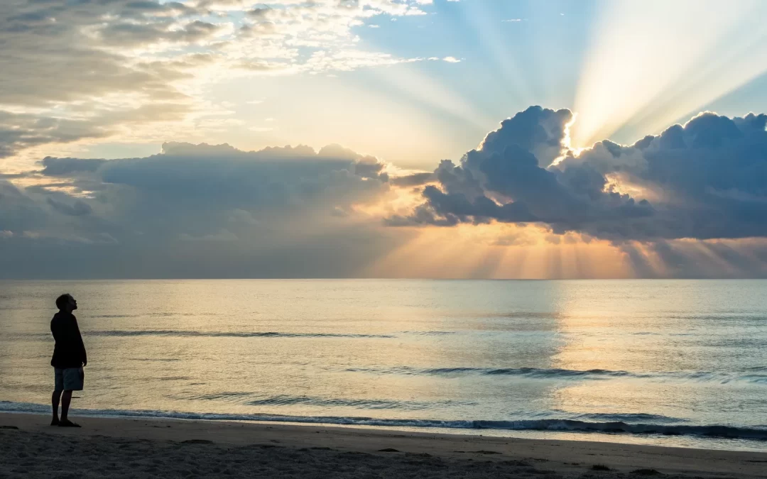 A person experiencing a spiritual awakening while watching the sunrise over the ocean.