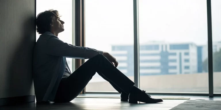 A person sitting alone and looking distressed, contemplating if they have religious trauma.