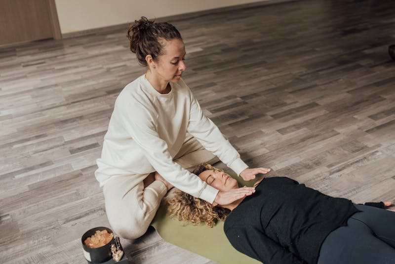 A practitioner performing Reiki spiritual healing on a person lying peacefully, demonstrating energy work techniques