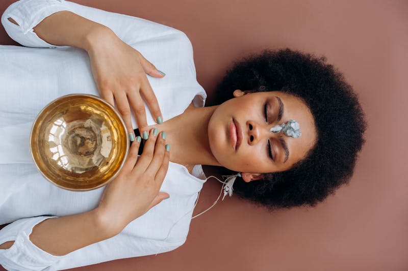 A woman meditating with a Tibetan singing bowl and healing crystals during a spiritual healing practice
