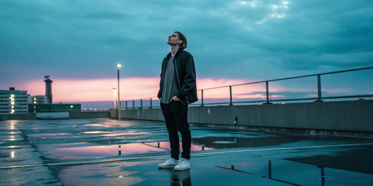 A person alone on a rooftop at sunset, feeling the spiritual disconnection from God.